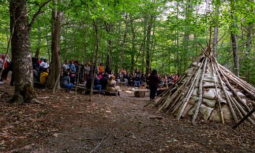 Tourism students gathered in wooded area next to a wigwam in Kejimkujik National Park
