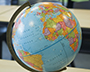 A globe sits on a desk in a classroom.