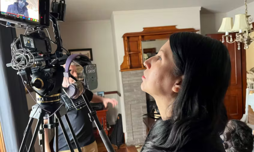 Creepy Cape Breton" creator and director Dawn Wells watches footage live on a monitor during a production shoot in a living room set.