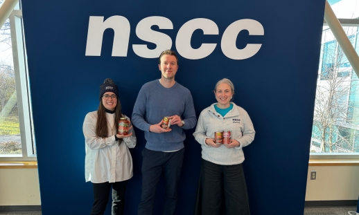 From left to right, photo NSCC Foundation employees Caitlin McKellar, Ben Trenaman and Lauren Caines holding food in front of NSCC sign.