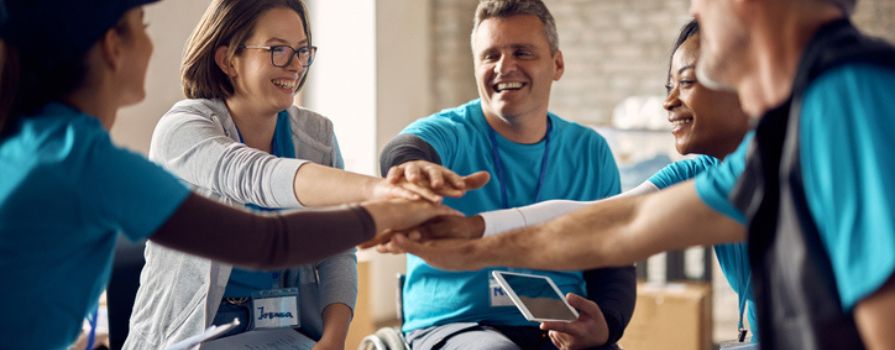 Five people in a circle have their hands on top of one another.