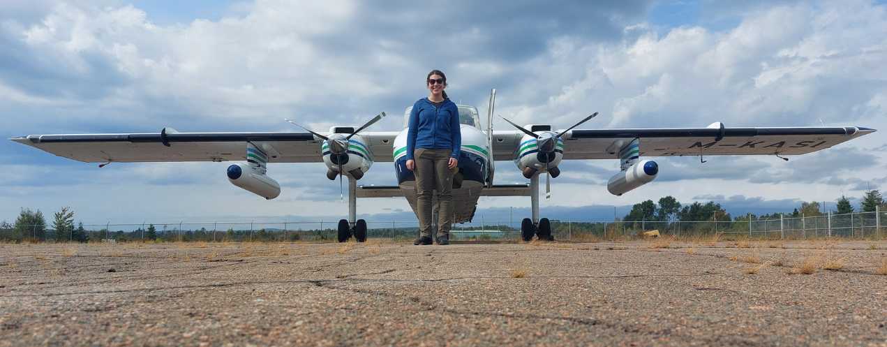 A woman standing in front of a small aircraft equipped with the lidar system.