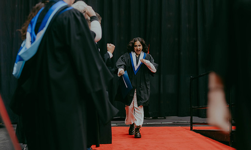 An NSCC graduate joyfully walks across the Convocation stage to receive their credential.