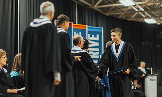 An NSCC graduate recieves their diploma on the Convocation stage.