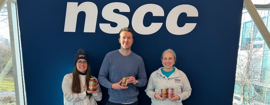 From left to right, photo NSCC Foundation employees Caitlin McKellar, Ben Trenaman and Lauren Caines holding food in front of NSCC sign.