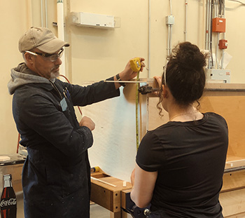 Cabinetmaking instructor Steve and student Mackenzie inspect a cabinet project.