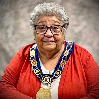 A woman wearing a red sweater and a mayoral collar.