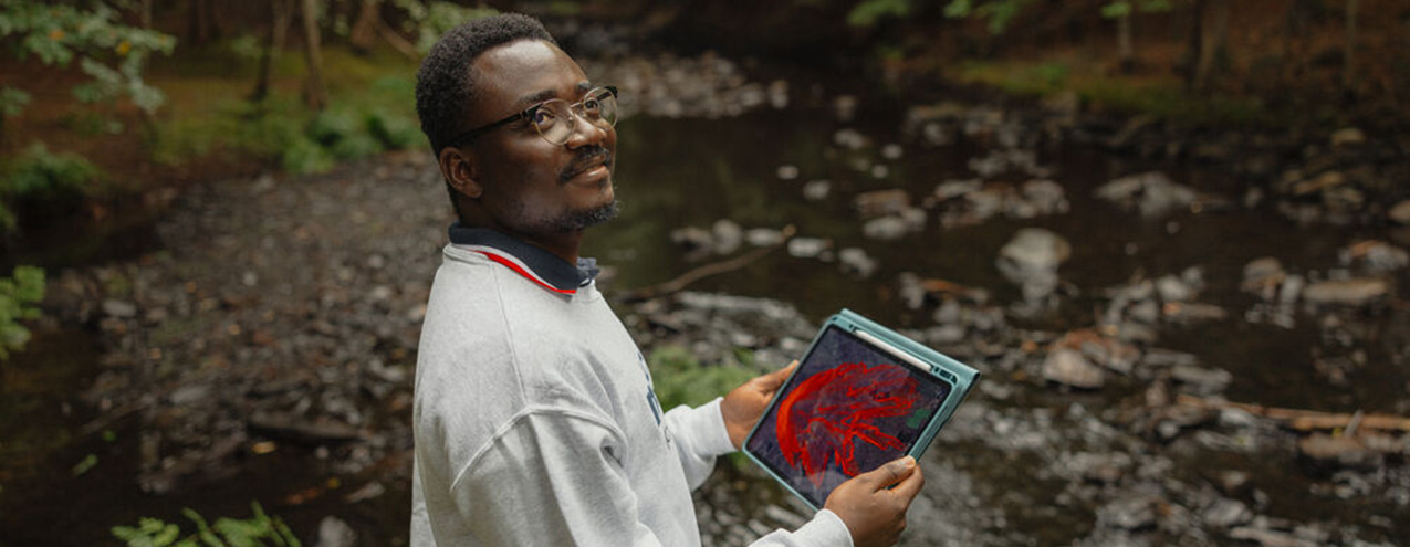 A person standing in the woods with an iPad in their hands.