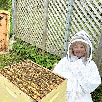 Student covered in protective clothing while viewing an active beehive