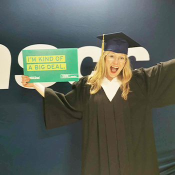 Natasha expressing excitement while wearing a graduation cap and gown