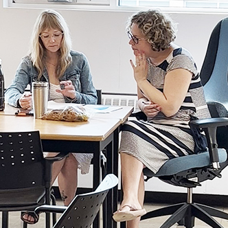 Natasha and instructor sitting at a desk together looking at a book