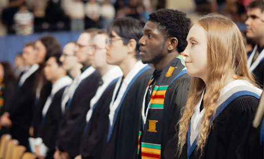 A photo of grads standing during their graduation ceremony.