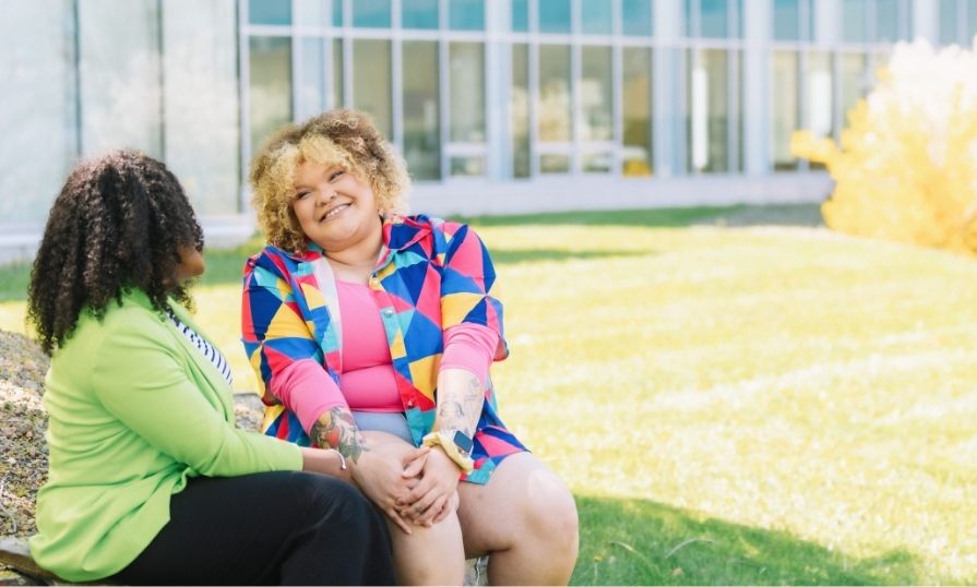 An NSCC student and employee smiling and talking outside on campus.