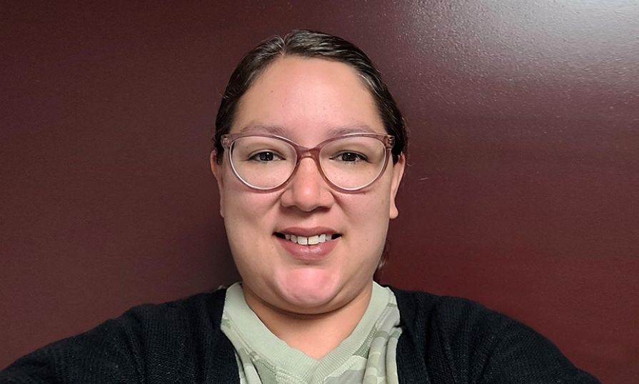 A woman, Carrie Anne Michael, stands in front of a door.