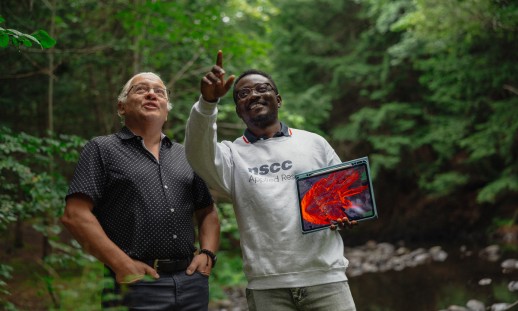 Two people in a forest setting reviewing fire simulation software on a tablet.
