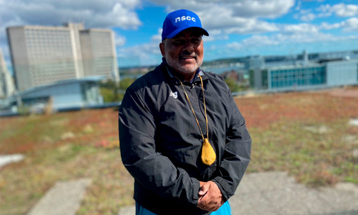Person with arms crossed standing in front of the Halifax harbour.