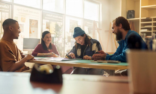 A group of students are working together at a table, smiling and laughing.