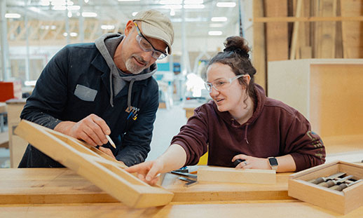 A student and faculty member work together in a woodshop.