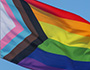 A close-up photo of Progress Pride flag shown waving in the wind.