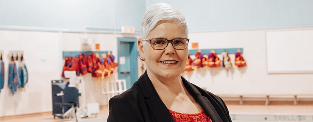 Cindi Green, an NSCC graduate, stands in front of a pool, smiling at the camera.