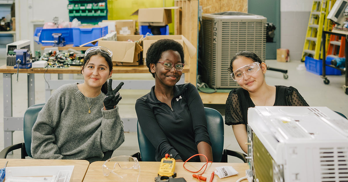 Three youth sit together at a table during an NSCC Youth Skilled Trades Camp.