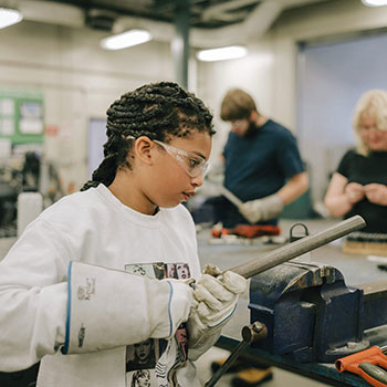 A youth works with a clamp and a piece of metal during at an NSCC Youth Skilled Trades Camp.