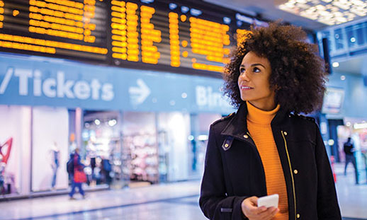 A hospitality and tourism student holds a phone in an airport.