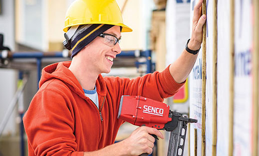 A student in one of NSCC’s carpentry programs uses a tool to construct a wooden frame for a wall.