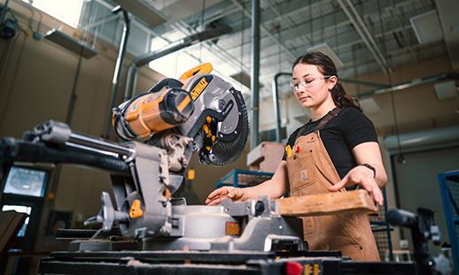 A student cutting a piece of wood while studying through NSCC carpentry courses.