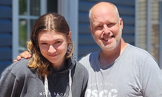 Scott Mackay and his daughter Genevieve wear grey t-shirts with the NSCC logo and smile.
