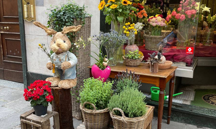 Italian flower shop with colorful blooms, herbs, and a bunny figure at entrance