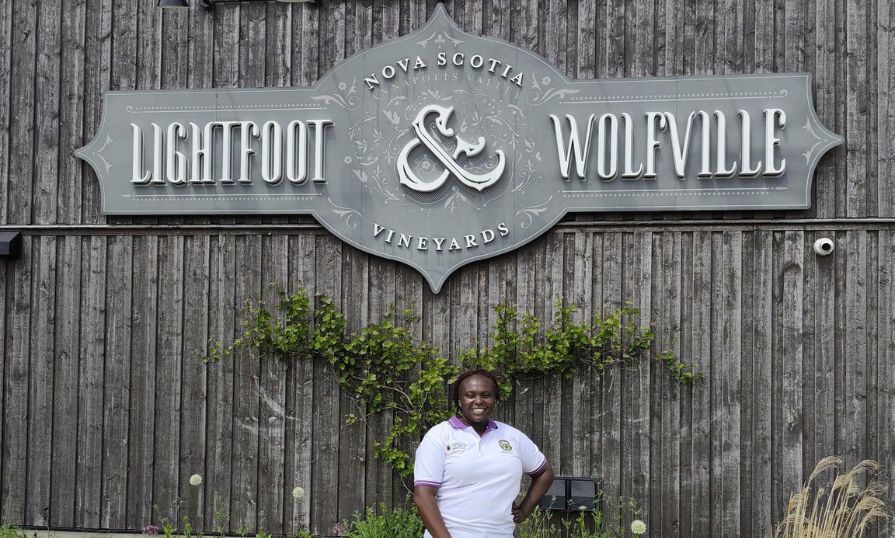 Moureen C. Kosgey smiles in front of Lightfoot & Wolfville sign.