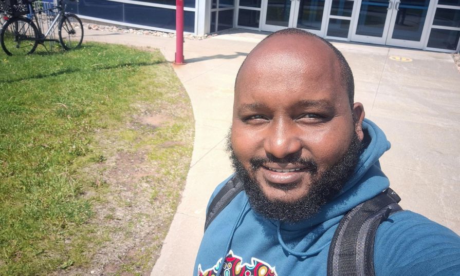 William Masila Kithiia smiling outdoors in front of the NSCC Building